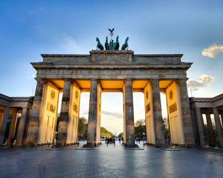 Our Destinations The iconic Brandenburg Gate in Berlin, captured during sunset with glowing light.